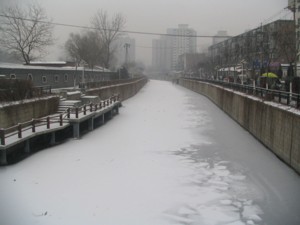 The snowfall turns everything white, the canal water is frozen
